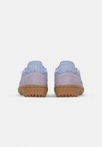 Sneakers in suede viola con un contra tallone azzurro chiaro, suola in gomma e marchio "NIKE" in rosa sul retro. Design a basso profilo.