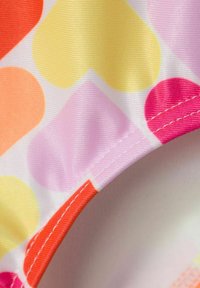 Tejido de traje de baño con una textura suave que presenta un colorido patrón de corazones en tonos naranja, amarillo, rosa y púrpura, y un borde cosido.