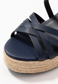 Námořnické kožené platformové sandály s tkanou juty, s křížovým designem pásků a hladkým, zaobleným špičkou.
