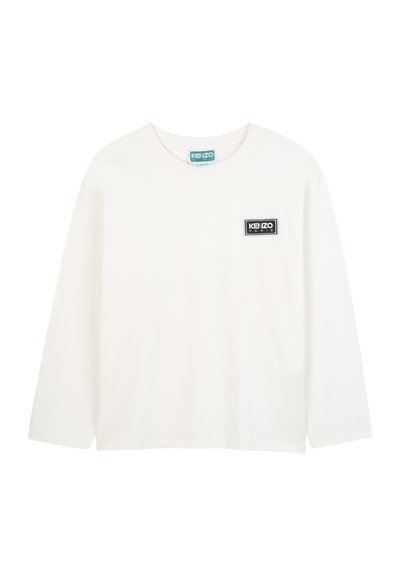 Biała koszulka z długim rękawem z bawełny, z prostokątną czarno-białą naszywką logo na klatce piersiowej, okrągłym dekoltem i luźnym krojem.