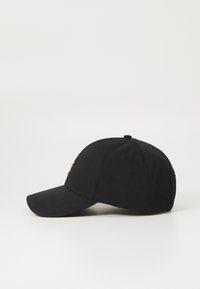 Svart baseballcaps med buet brem, laget av stoff, med et brodert logo i gull foran, teksturert overflate og luftehull.