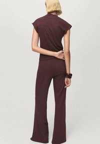 Maroon knit top with cap sleeves paired with matching flared pants. Smooth texture and simple design. Accessorized with a dark bangle.
