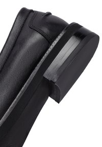 Botín negro de piel con acabado brillante, punta redondeada y tacón cuadrado. Costuras detalladas a lo largo de la parte superior y textura suave.