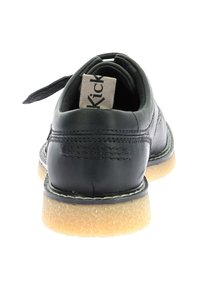 Scarpa in pelle nera con retro arrotondato, pelle testurizzata, suola in gomma color nocciola e una piccola etichetta di tessuto attaccata sul retro.