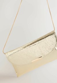 Kuldse metallilise läikega käekott, millel on pragunenud tekstuur, voltuv klapp ja kuldne ketirihm. Omaduseks õrn ristkülikukujuline kinnituse detail.