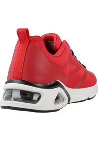 Scarpa da atletica rossa con upper testurizzato, dettagli neri e una unità di ammortizzazione ad aria visibile nella suola bianca.