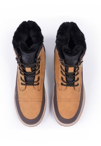 Braune Leder-Stiefeletten mit schwarzem Kunstfellfutter, runder Zehenpartie, strukturiertem dunklen Absatz und schwarz-gelben gesprenkelten Schnürsenkeln.
