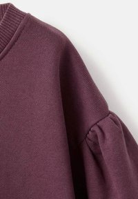 Purple knit sweater section featuring a ribbed neckline and puffed sleeves, with a smooth texture and even stitching detail.
