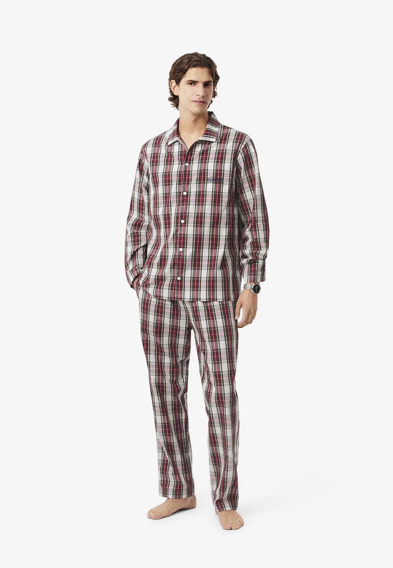 Piros és szürke kockás pizsama szett, puha anyagból készült, gombos felsővel, hosszú ujjakkal és megfelelő nadrággal, mely rugalmas derékkal rendelkezik.