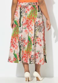 Jupe midi florale avec une base rose clair, présentant des motifs vifs de paon vert et de feuilles rouges, avec une taille élastique et une coupe fluide.