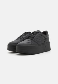 Black platform sneakers with a smooth leather texture, round toe, lace closure, and horizontal stripes on the sides.