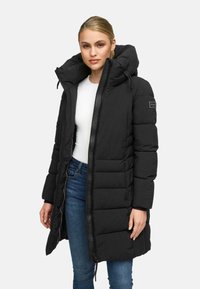 Black puffer coat with a high collar and hood, featuring a padded design, zip front, and side pockets. Subtle logo detail on sleeve.