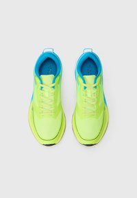 Ténis de desporto amarelo-neon com detalhes em azul, parte superior de malha respirável, língua e atacadores acolchoados, apresentando uma sola texturizada para aderência.