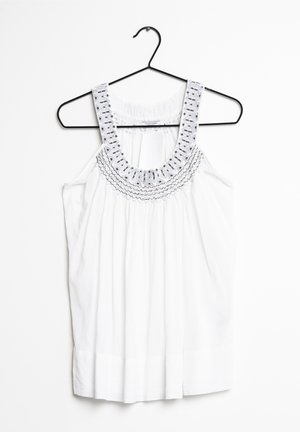 Weißes ärmelloses Oberteil mit besticktem rundem Ausschnitt, versehen mit dezenten Falten und einer glatten Textur. Hängt an einem schwarzen Metallbügel.