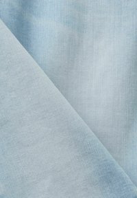 Lys blå denimstof med en glat tekstur og en let glans, der viser diagonale vævemønstre. Blødt og fleksibelt materiale.