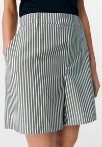 Stribede shorts i grå og hvid, med flad front, sidelommer og en afslappet pasform med en let kant. Lavet af letvægtigt stof.