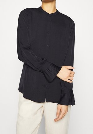 Black long-sleeve shirt with a round collar, button closure, and pleated cuffs; made from lightweight fabric with a smooth texture.