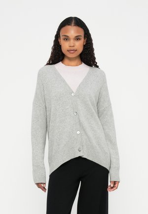 Grijze cardigan met een v-hals, knopen aan de voorkant en een dropped schouderlijn. Zachte gebreide textuur, geribbelde manchet en zoom. Gestyled over een lichtroze top.