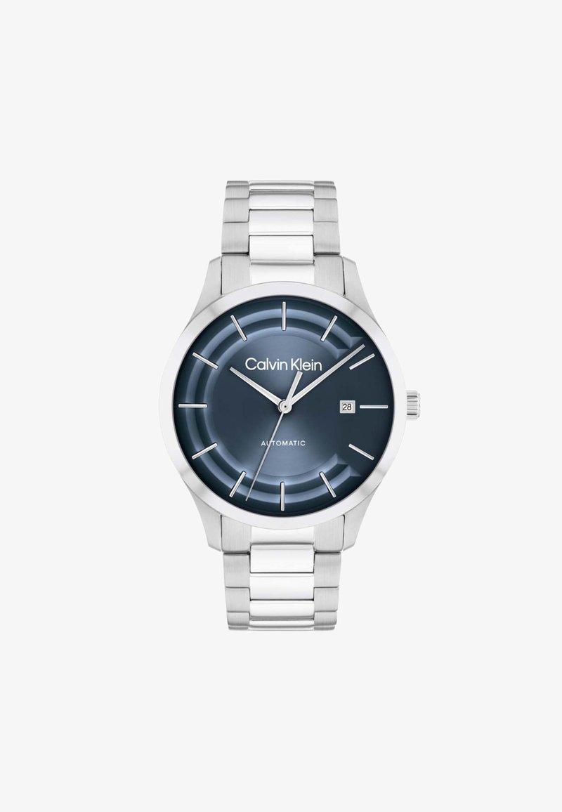 Montre-bracelet en métal argenté pour homme Calvin Klein avec cadran bleu foncé, index des heures argentés, guichet de date à 3 heures et trois aiguilles indiquant 10:10:39.