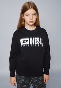 Felpa nera con un audace logo "DIESEL" bianco con effetto sfumato. Realizzata in cotone, con polsini a costine e design a girocollo.