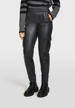 Schwarze Leder-Jogginghosen mit einem elastischen Bund, seitlichen Taschen und einer Cargo-Tasche. Glatte Textur und schmaler Schnitt am Knöchel.