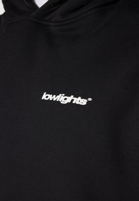 Black hoodie with a soft texture, featuring a white "lowlights" logo on the chest. Hooded style, minimalistic design.