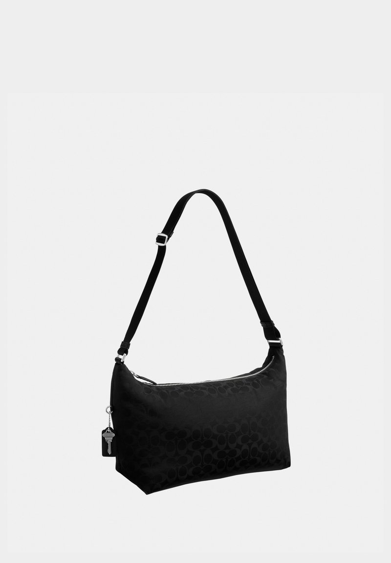 Bolso de hombro negro con correa ajustable, cierre de cremallera y patrón sutil, con un pequeño llavero metálico adjunto.