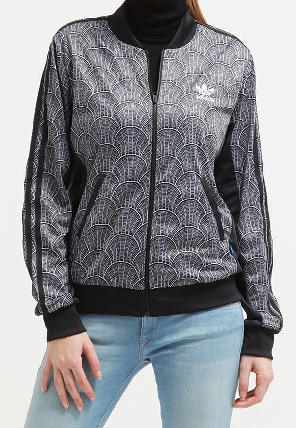 Bílá a černá bomber bunda s vlnkovým vzorem, žebrovaným límcem, bočními kapsami a kontrastními plnými černými rukávy. Zapínání na zip.