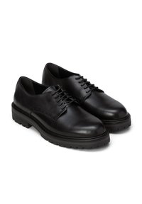 Czarne skórzane buty sznurowane, o gładkim wykończeniu, zaokrąglonym nosku i teksturowanej gumowej podeszwie z akcentami i minimalnymi perforacjami.