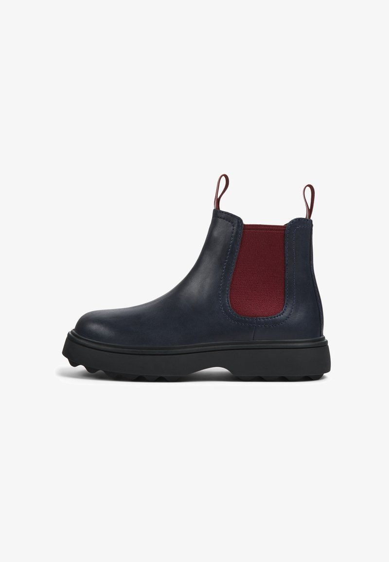 Bottines Chelsea en cuir bleu foncé avec des panneaux élastiques rouges sur les côtés, des tirettes et des semelles en caoutchouc noir texturé. Bout arrondi et design épuré.