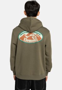 Hoodie verde oliva con una grande grafica di montagna in arancione e teal sul retro. Presenta un cappuccio con lacci e polsini a coste.