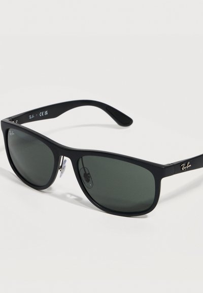 Черни слънчеви очила Ray-Ban с правоъгълни тъмни стъкла и регулируеми носови подложки на бял фон.