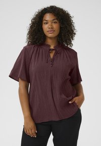 Burgundy short-sleeve blouse with a buttoned front and tie neck detail; features a textured, crinkled fabric and relaxed fit.
