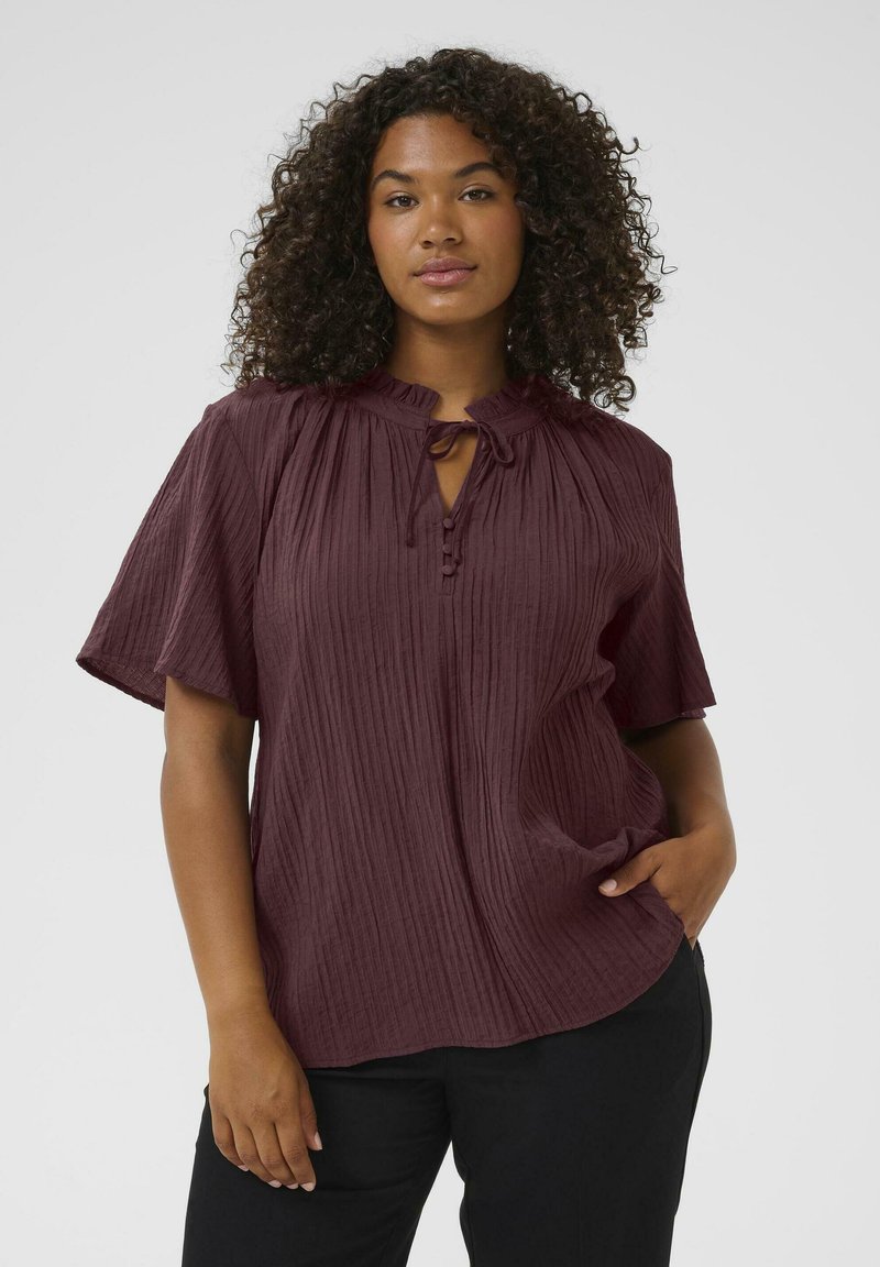 Burgundy short-sleeve blouse with a buttoned front and tie neck detail; features a textured, crinkled fabric and relaxed fit.