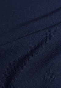 Marineblaue Stoff mit einer glatten, strukturierten Oberfläche. Verfügt über ein dezentes Rippmuster und einen leichten Glanz, der die weiche und leichte Beschaffenheit betont.