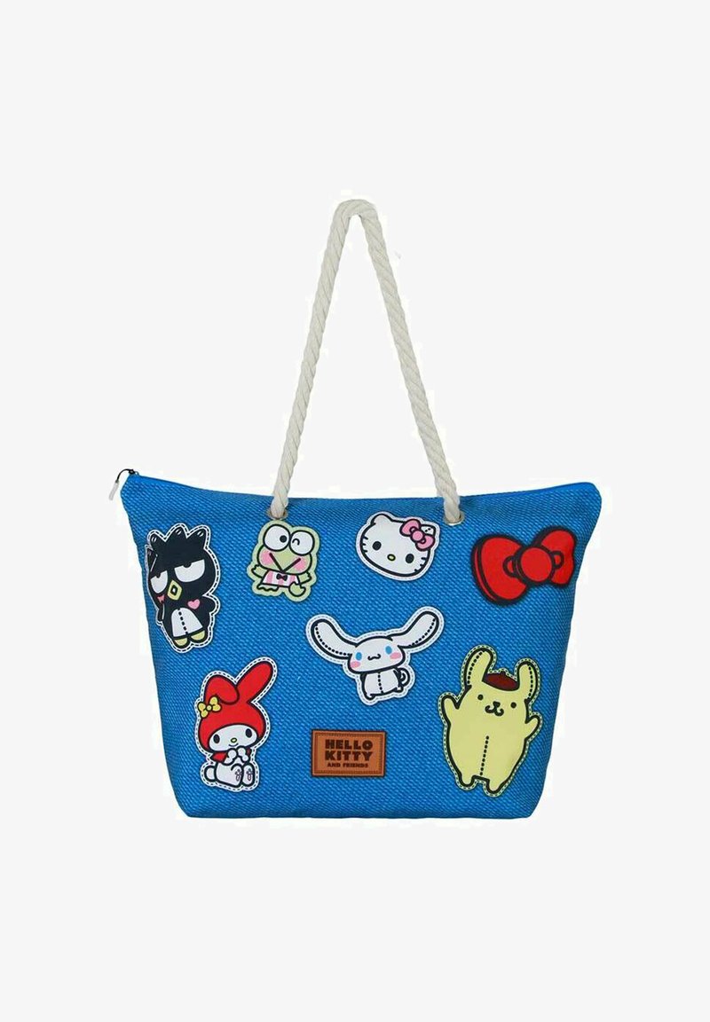 Bolsa tote azul con un acabado texturizado, que presenta varios parches de personajes coloridos y un asas de cuerda. Etiqueta de la marca en la parte inferior.