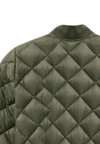 Gepatchter olivgrüner Mantel mit strukturierter Oberfläche, der über Diamantmuster und einen gerippten Kragen verfügt. Das Material scheint weich und leicht zu sein.