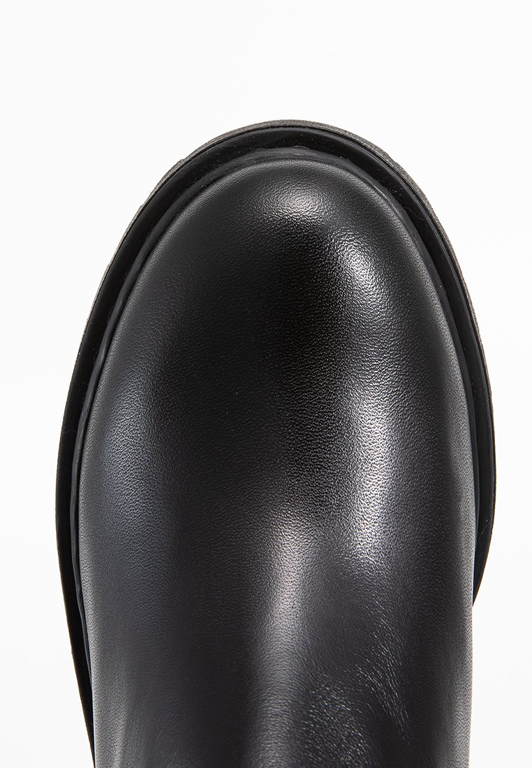 Close-up van de gladde zwarte leren laarsneus met ronde vorm en zichtbare stiksels langs de rand.