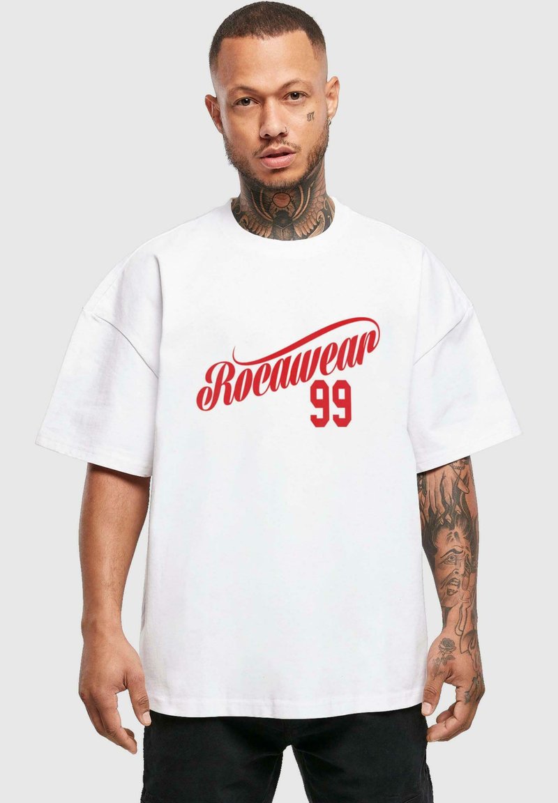 Bílé oversized tričko vyrobené z bavlny, s červeným logem "Rocawear 99". Krátké rukávy, kulatý výstřih a volný střih.