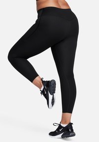 Sorte trenings leggings med høy midje og sidesømmer, kombinert med svart og hvite Nike-sneakers med polstret såle.