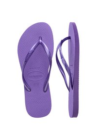 Lila flip-flop papucs, érdes gumi talppal, vékony pántokkal és domború logóval. A pántok és a talp egységes lila árnyalatúak.