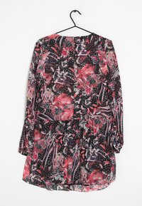 Robe longue à manches longues à motif floral avec une base noire, ornée de motifs roses et verts, en tissu léger et avec un col rond.