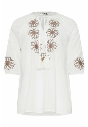 Blouse blanche avec encolure ronde, broderie florale marron sur le devant et les manches, et lien devant avec pompons blancs.