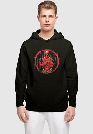 Black hoodie featuring a graphic print of a red-suited character in a circular frame with a distressed effect and front pocket.