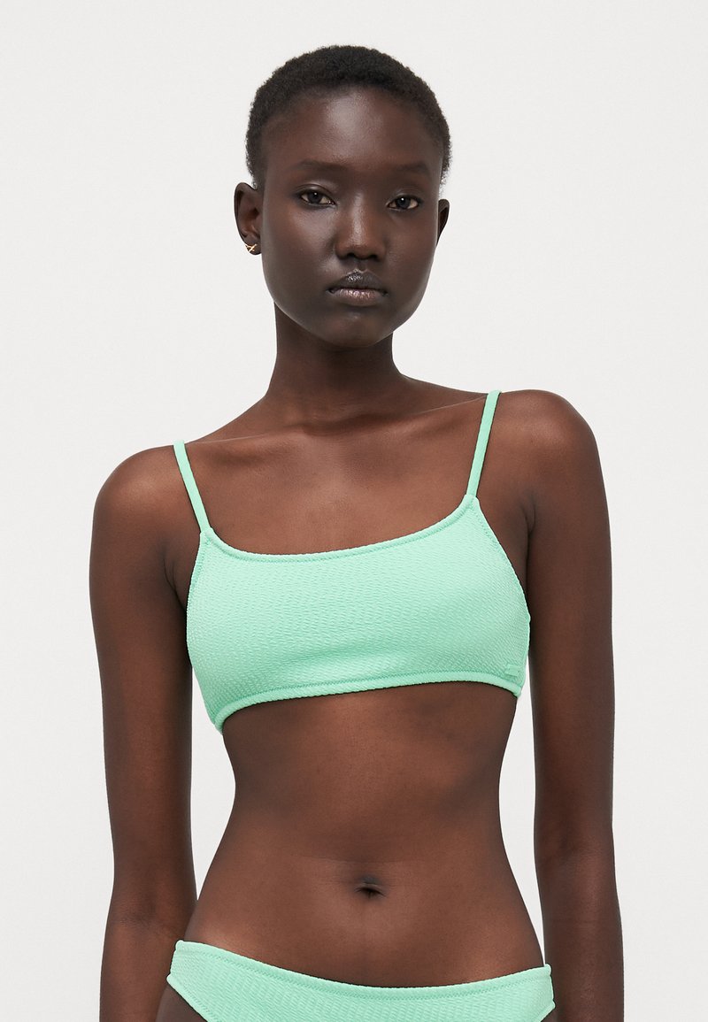 Top bikini verde menta con sottili spalline regolabili, tessuto testurizzato e forma rettangolare. Senza imbottitura, design corto.