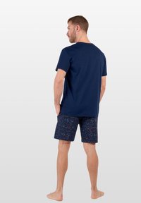 Marineblå bomullströja kombinerad med mönstrade shorts som har små, flerfärgade blommönster på en mörk bakgrund.