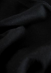 Crni materijal s glatkom teksturom, prikazuje draperirane nabore. Čini se da je tkanina lagana i ima suptilan sjaj, ističući svoju kvalitetu.