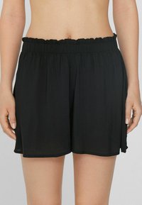 Shorts noirs en tissu léger, dotés d'une taille élastique à volants, d'une coupe ample et d'un ourlet qui tombe au milieu de la cuisse.