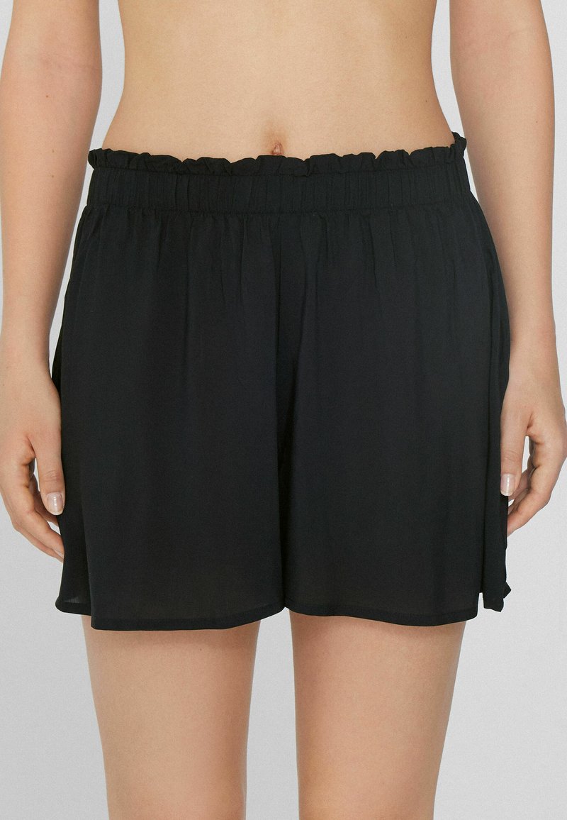 Shorts noirs en tissu léger, dotés d'une taille élastique à volants, d'une coupe ample et d'un ourlet qui tombe au milieu de la cuisse.