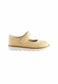 Gul läder Mary Jane-sko med en VELCRO-rem, perforerat mönster på tån och en vit gummisula. Slät textur, rundad form.